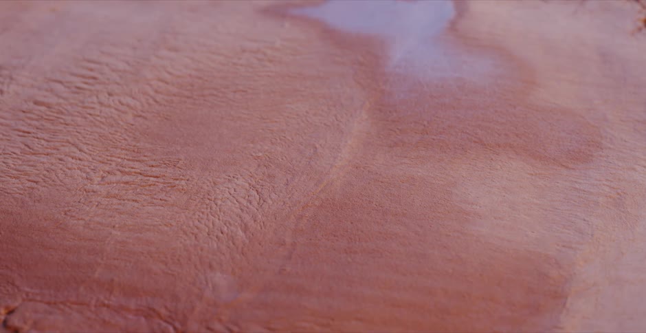 A blue body of water dries up and shrinks in a sandy landscape