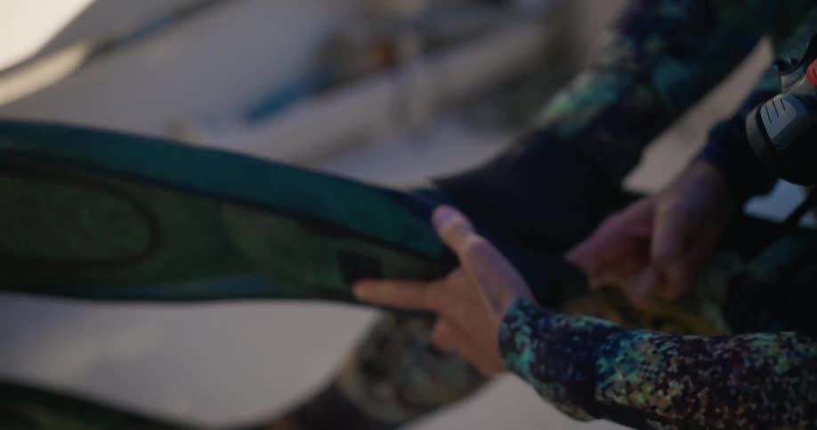 A person on a boat puts on fins before diving