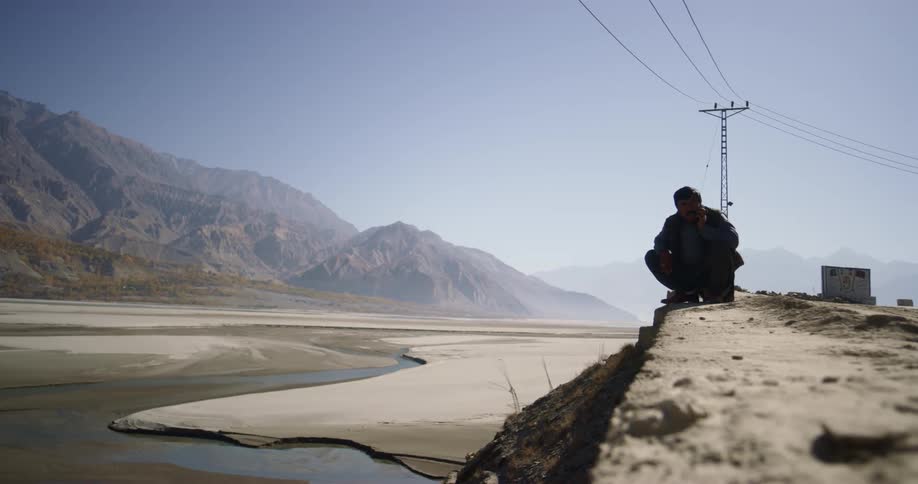 Man talking on phone near desert and mountains