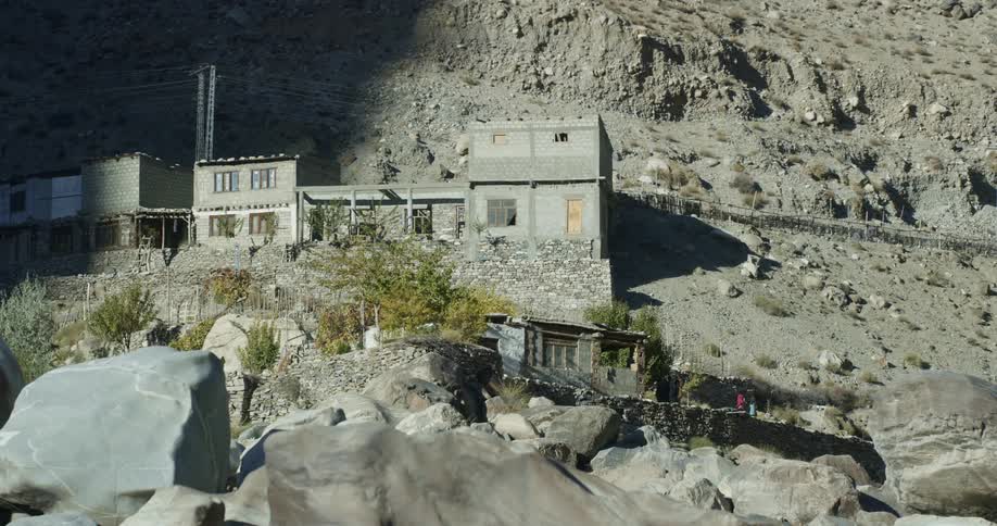 People walking on a path built on a cliff with buildings along it