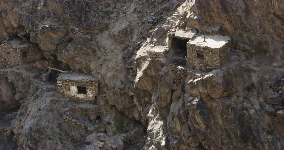 Primitive houses are built into the side of a mountain