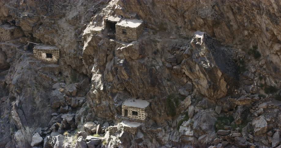 Primitive stone huts on the jagged slopes of a mountain