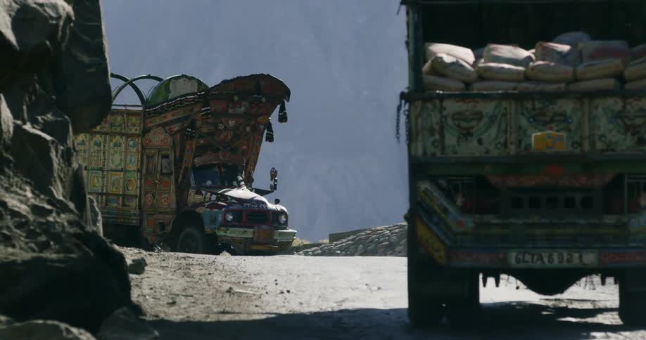 A road next to a cliff with trucks and rocks