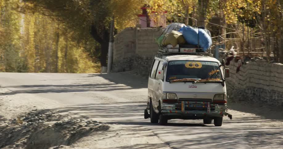 A vehicle driving on a road with trees and the sky in the background