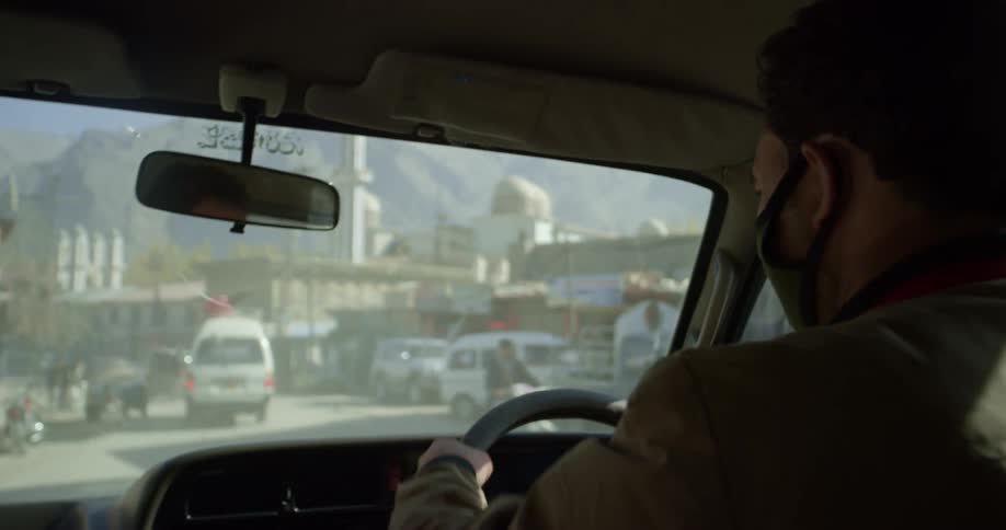 A male driving on a road in a city in a downtown area