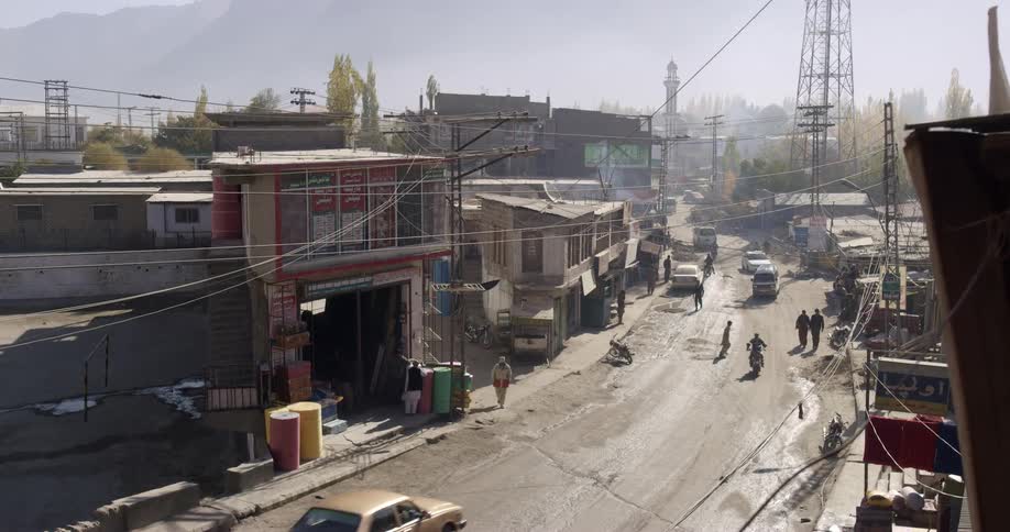 Traffic and pedestrians moving along a road in a small town during the day