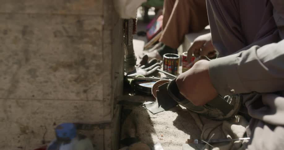 Street shoe repair man fixes a shoe using scissors and string