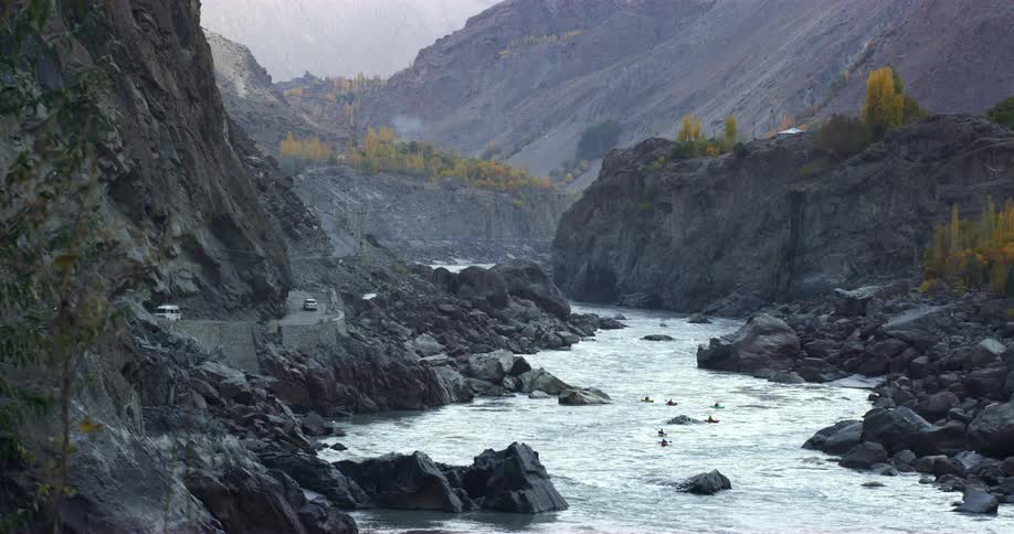 Kayaks travel down river between tall mountains