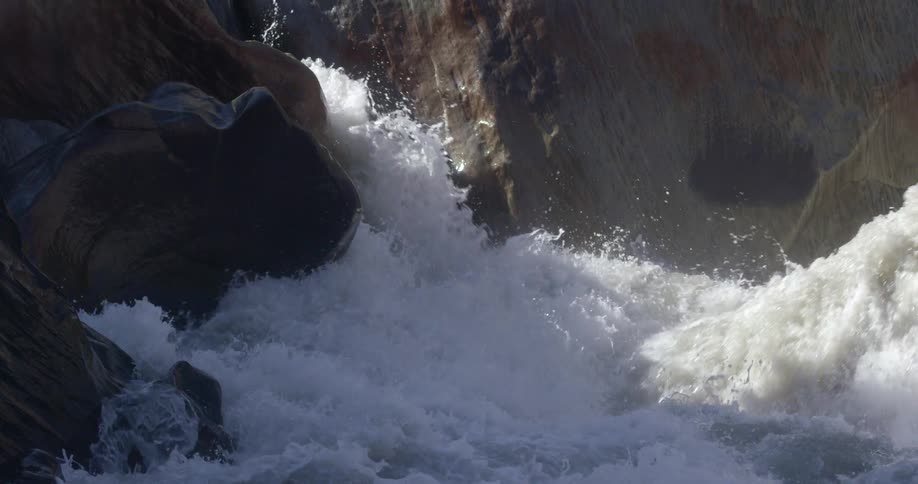 Water is splashing and foaming as it rushes downward along a rocky terrain
