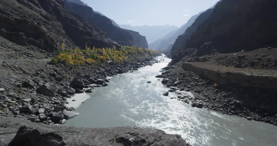 A long winding river flows through the mountains with rocks strown throughout