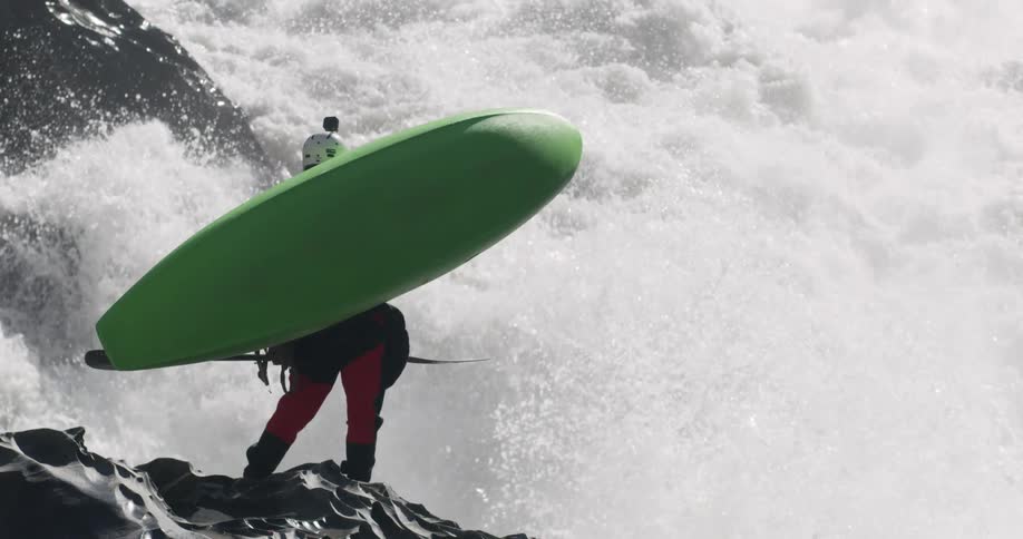 A person holds a canoe by the rapids