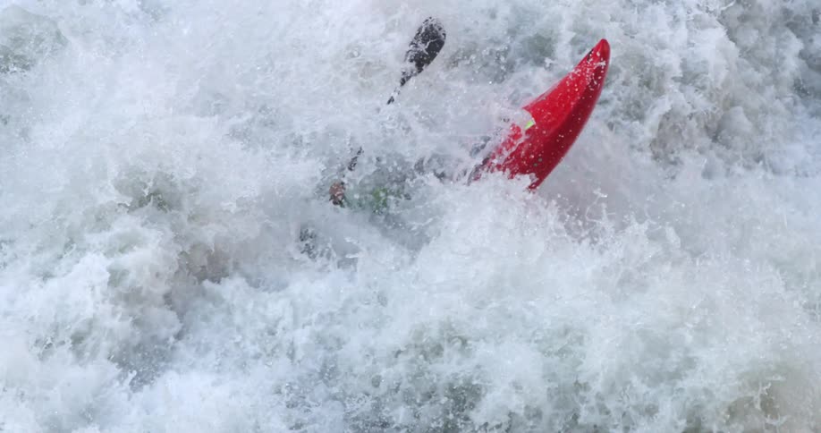 A person is tossed about as they kayak through river rapids