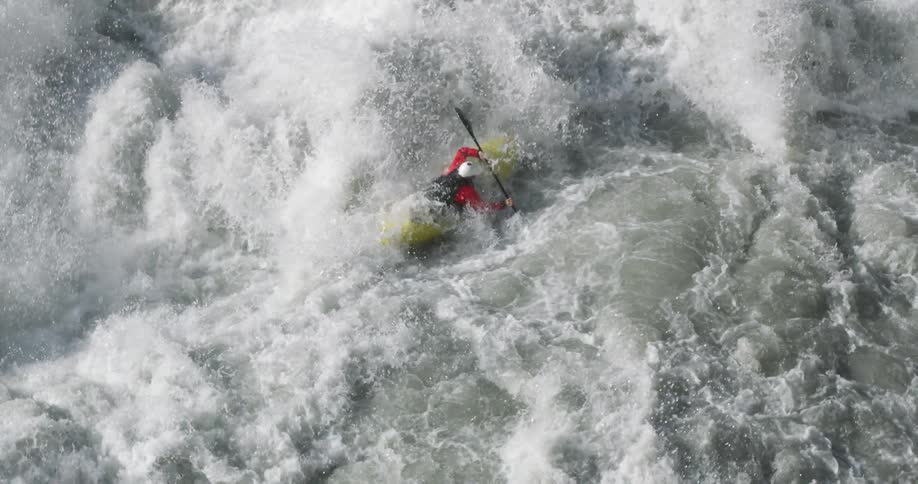 A person kayaking in rapids is tossed all over and goes under the water