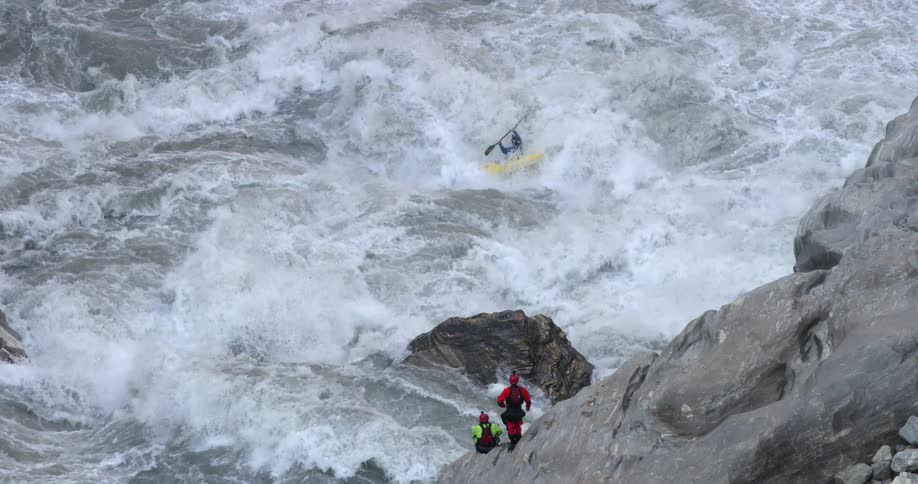 A person is flipped over in their raft in the rapids