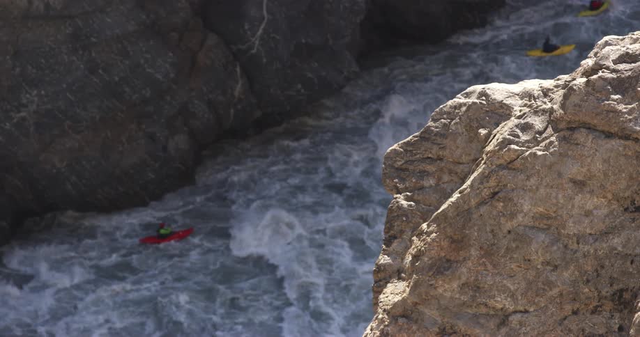 Group of people ride colorful kayaks on the turbulent waters of a rivers rapids