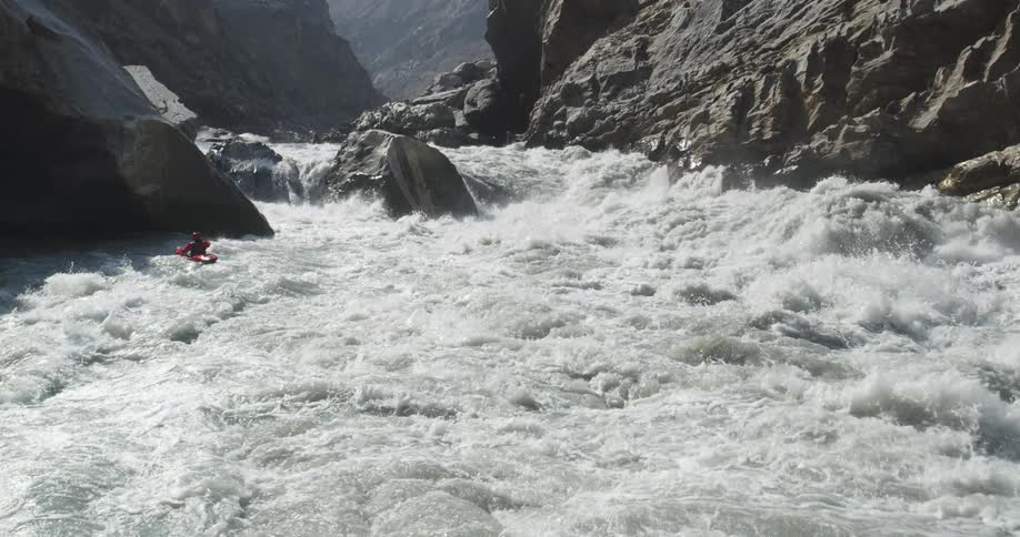 Man in a red kayak paddles on the turbulent waters of a rivers rapid