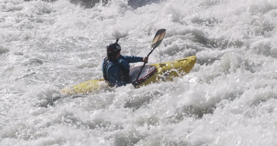 A kayaker struggles to paddle against the violent waters of a river