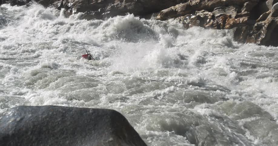 A kayaker paddles with the rushing flowing white water