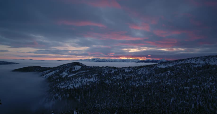 Time lapse of clouds passing over the pine forests on the snow covered mountains