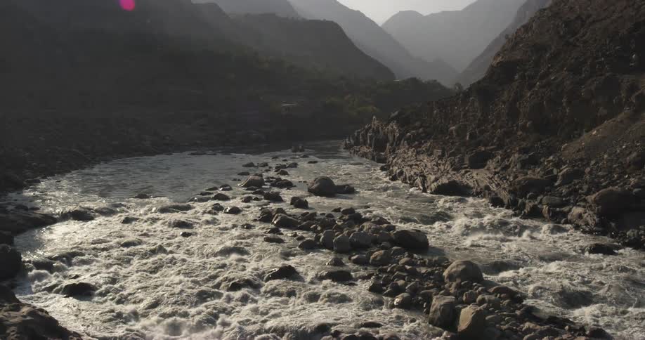 A stream with rocks and dirt with a mountain range and the sky in the background