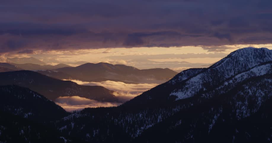 The sun is setting in the horizon above the mountains