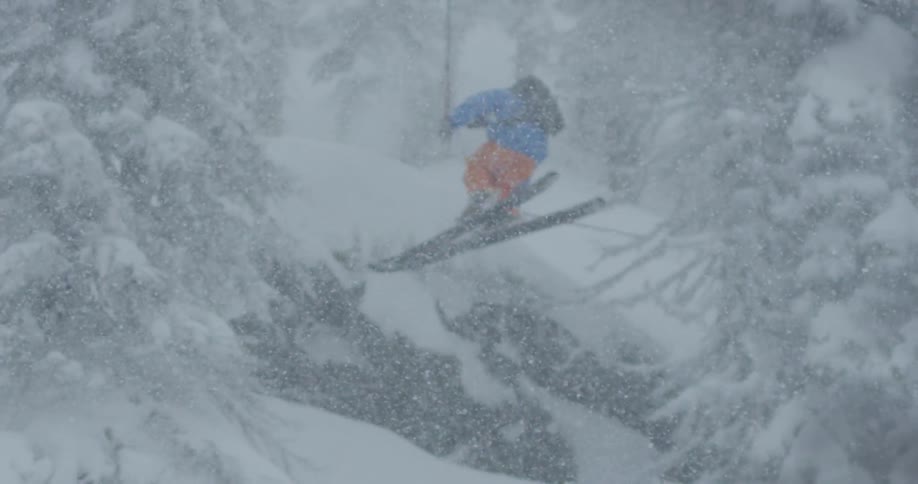 A skier jumps over a mountain ski jump during a snow storm