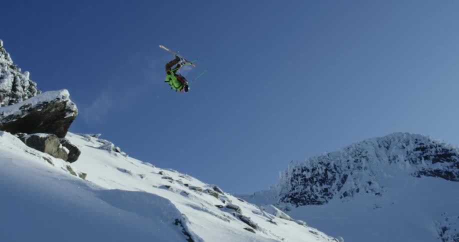 Skier jumps over a rock in the snow covered slopes of a mountain