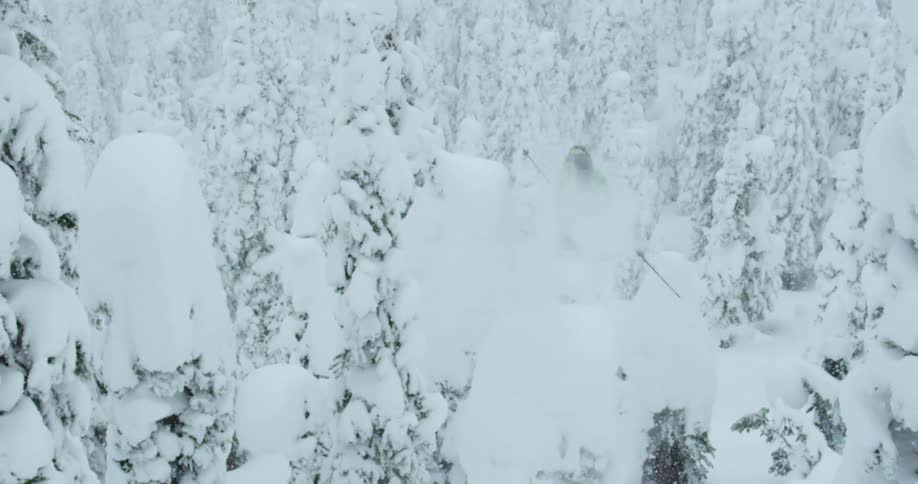 A person jumps over snow covered trees as they ski