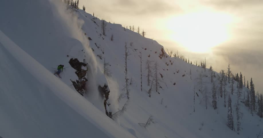 A skier navigates around a large rock formation on the slope of a mountain