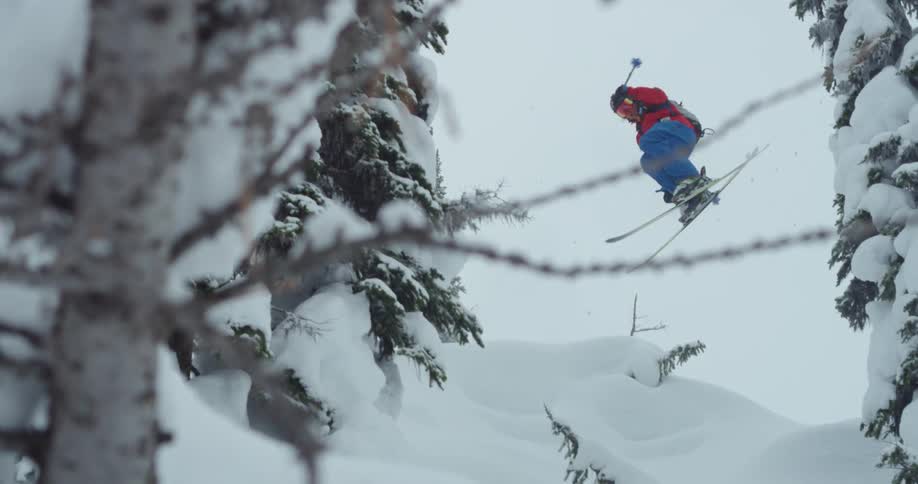 A skier going over a jump in snowy mountains