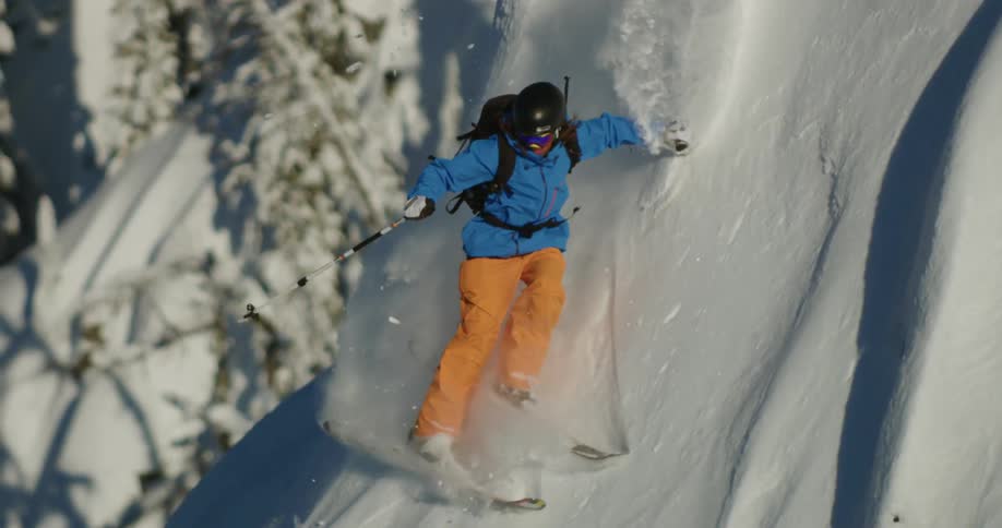 Person skis down steep snow covered slope