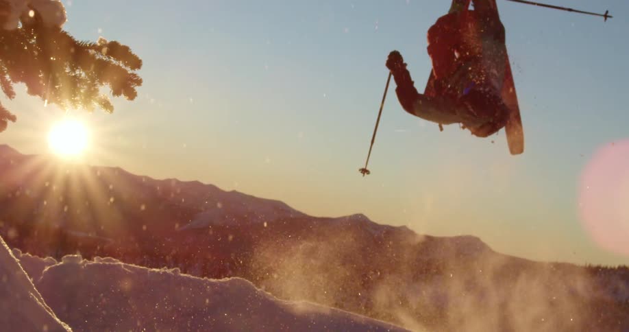 The sun shines down on a skier as they do a midair backflip over a hill