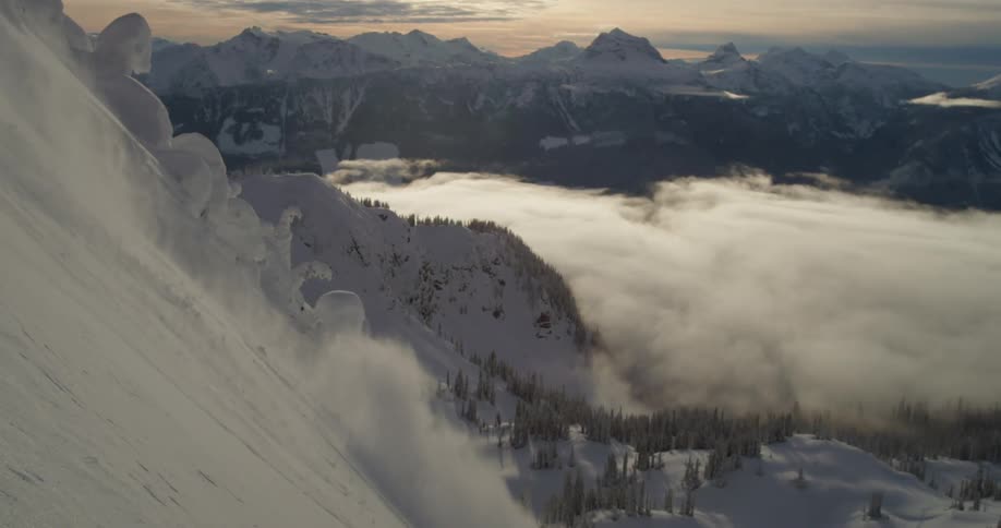 A skier descends a steep mountain slope during the day