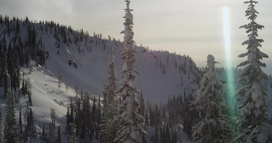 A person skiing down a snowy slope with the sky and clouds in the background