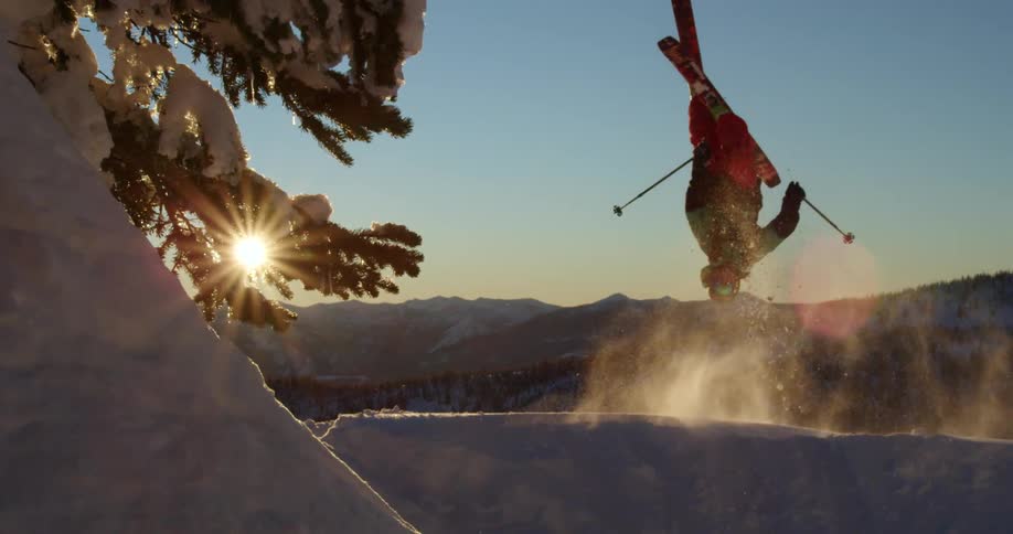 A skier doing a ski flip on a mountain cliff