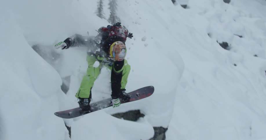 A person with a helmet and backpack snowboarding down a snowy slope