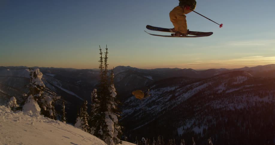 Skiers make ski jump on tall slope
