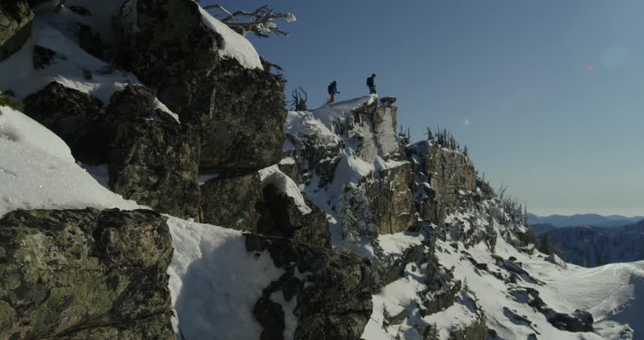Two hikers reach the peak of a snow covered mountain