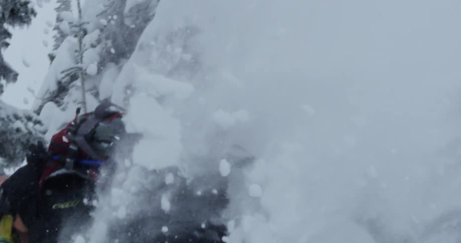 A snowboarder briefly goes airborne as they descend a snowy mountain slope
