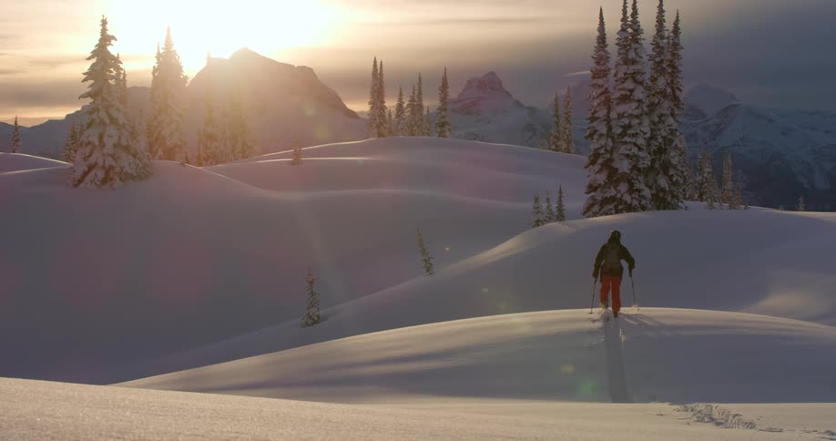 A skier hikes across snow covered hills in the mountains