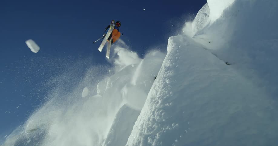 Person ski jumps off of cliff on snowy mountain