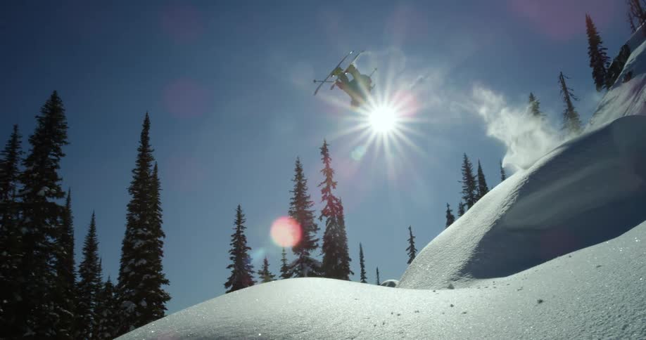 A skier goes over a jump in snowy mountains on a winter day
