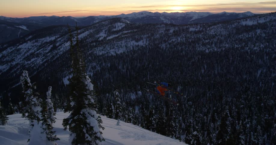 A person skiing flips in the air as they go down a mountain