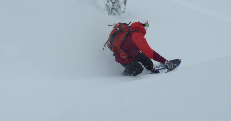 A person wearing snow gear is snowboarding down a snowy slope