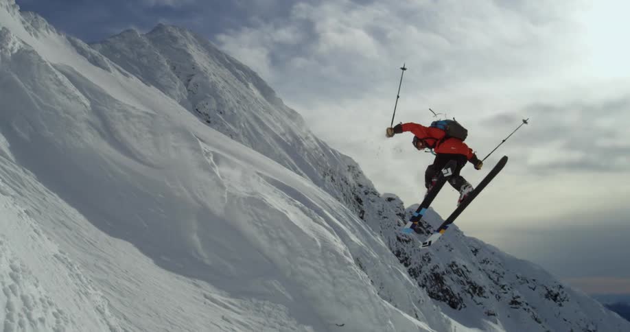 Person makes jump on skis from steep mountainside
