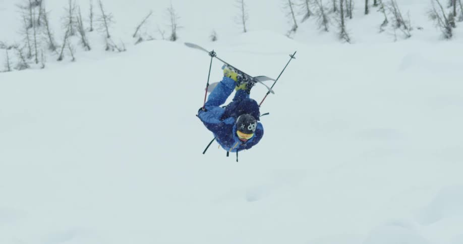 A man skiing jumps and flips in the air