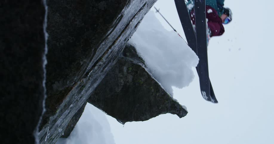 A person jumps as they ski over a rock