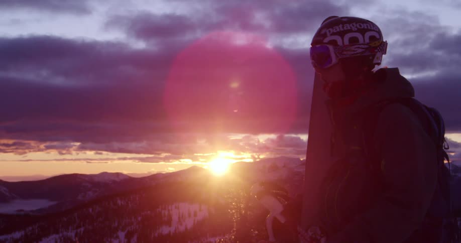 Person in ski gear stands in front of sunrise in mountains