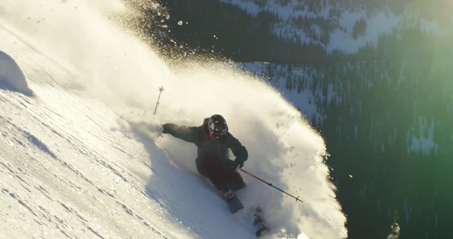 Skier slides down the snow covered slopes of a mountain at day