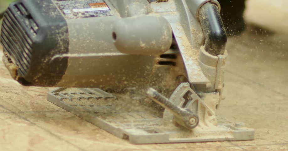 Saw rips through wood throwing sawdust to the side as it moves